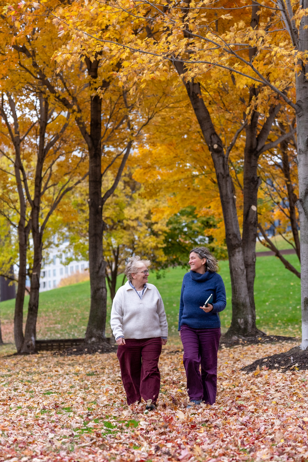 Poppy Potter walking and talking with a client along a path through autumn trees